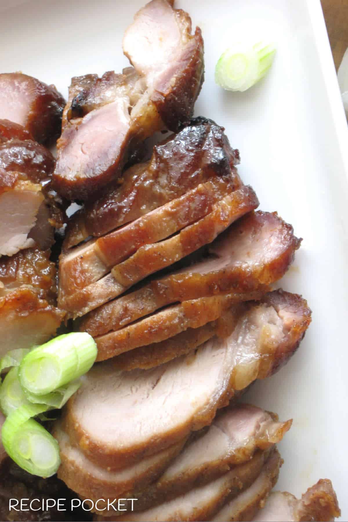 Closeup of Chinese barbecue pork slices garnished with spring onion.