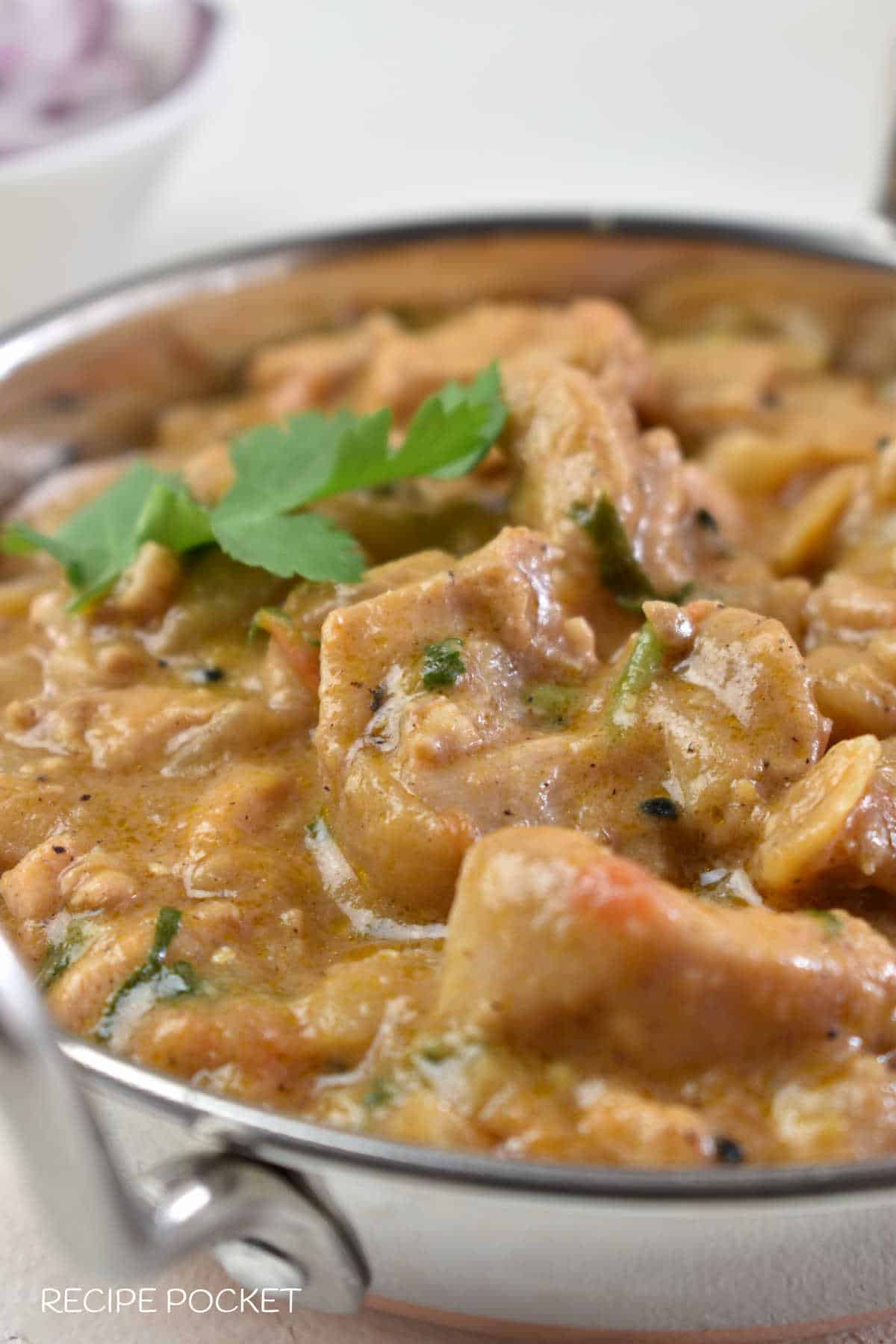 Cropped in close up of chicken balti curry in a silver dish.