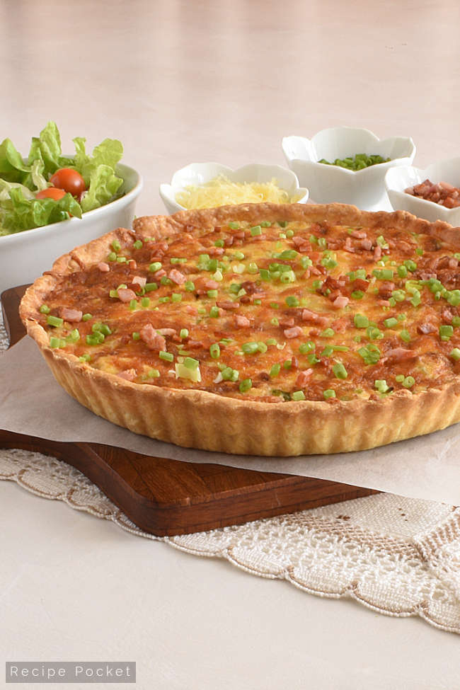 Quiche lorraine garnished with bacon pieces and chives.