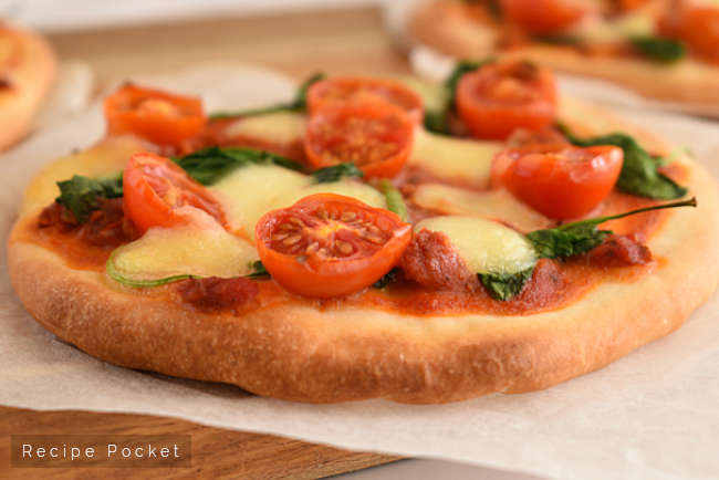 Pita bread pizza with tomato and spinach.