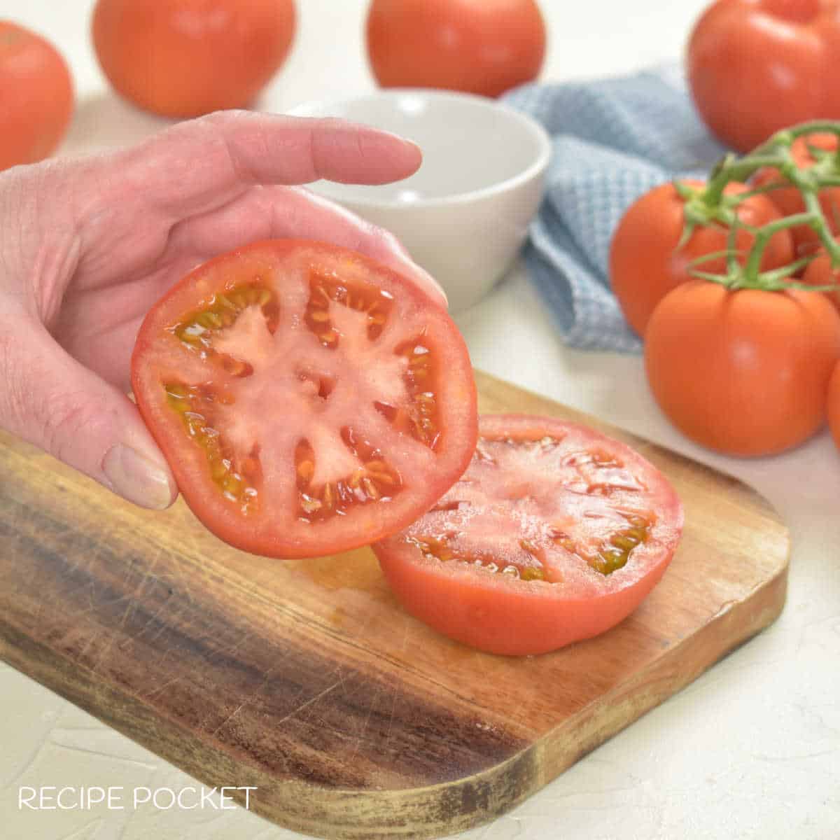 Hand holding half a tomato.