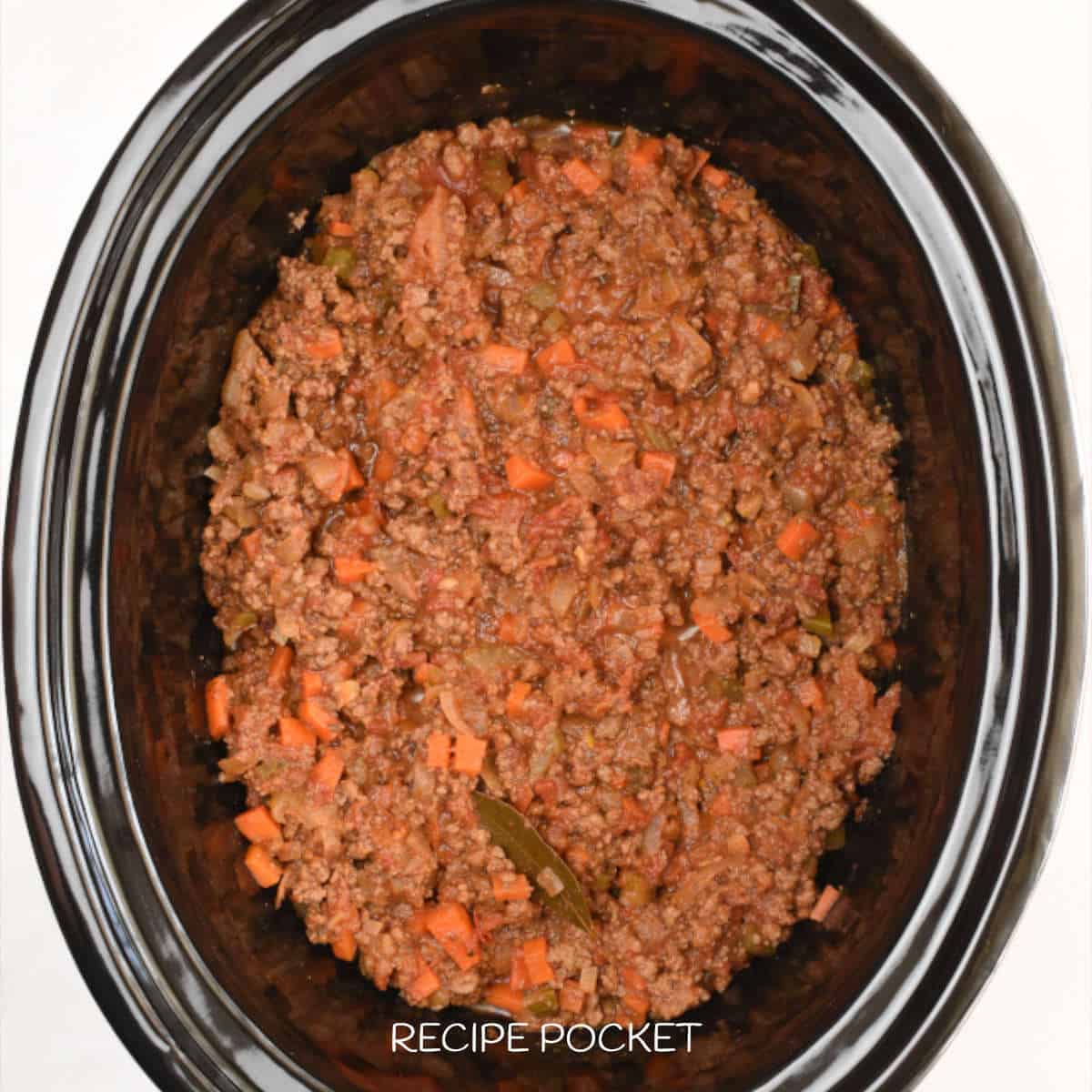 Cooked bolognese sauce in a black slow cooker bowl.
