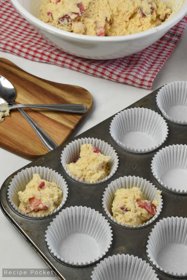 Muffin tin with muffin cases and strawberry yogurt muffin batter.