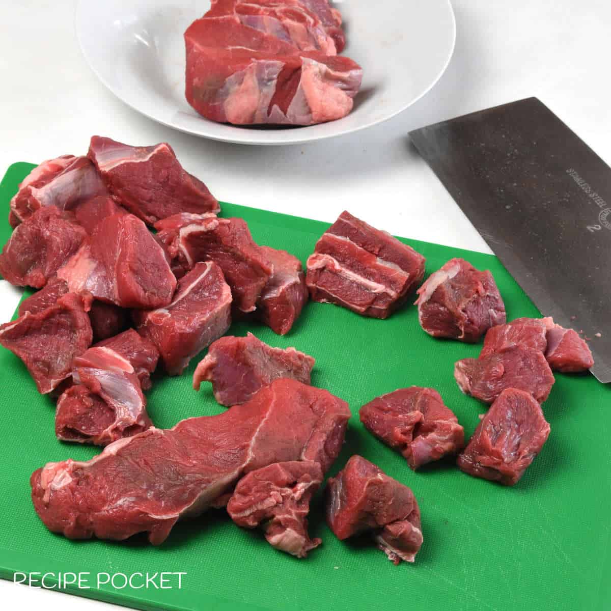 Cut pieces of meat on a green board.