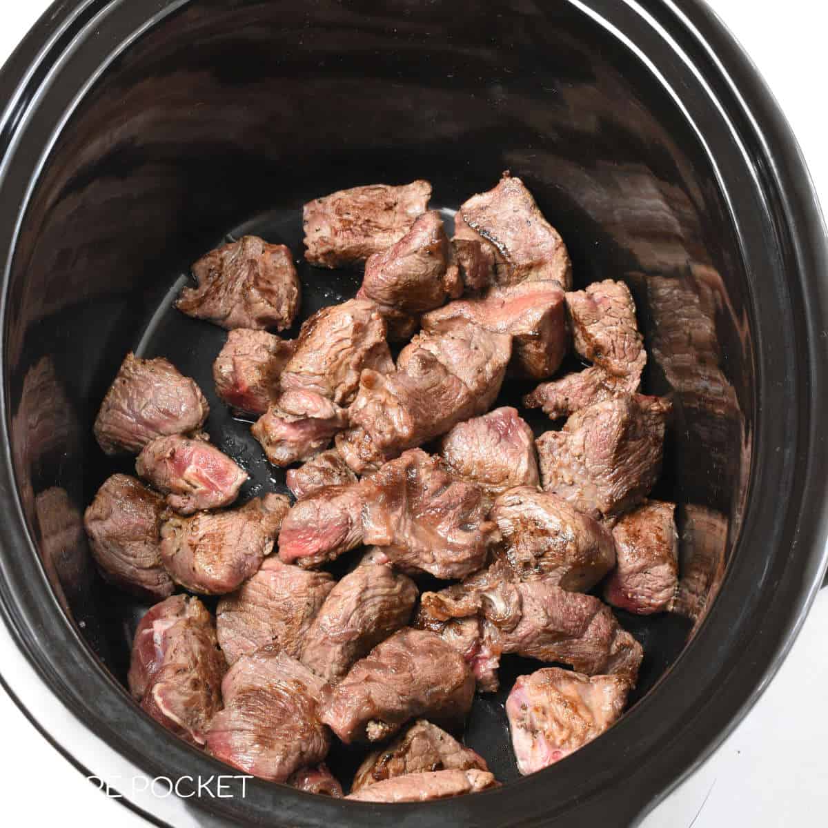 Fried meat pieces in a slow cooker bowl.