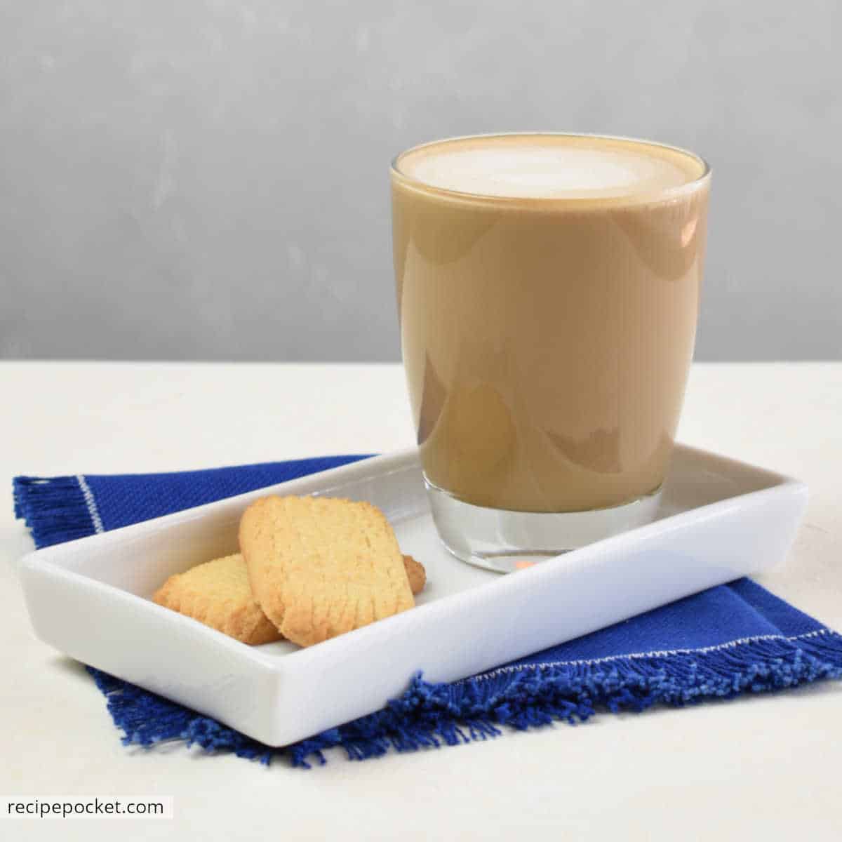 Flat white coffee on a white tray with two cookies.
