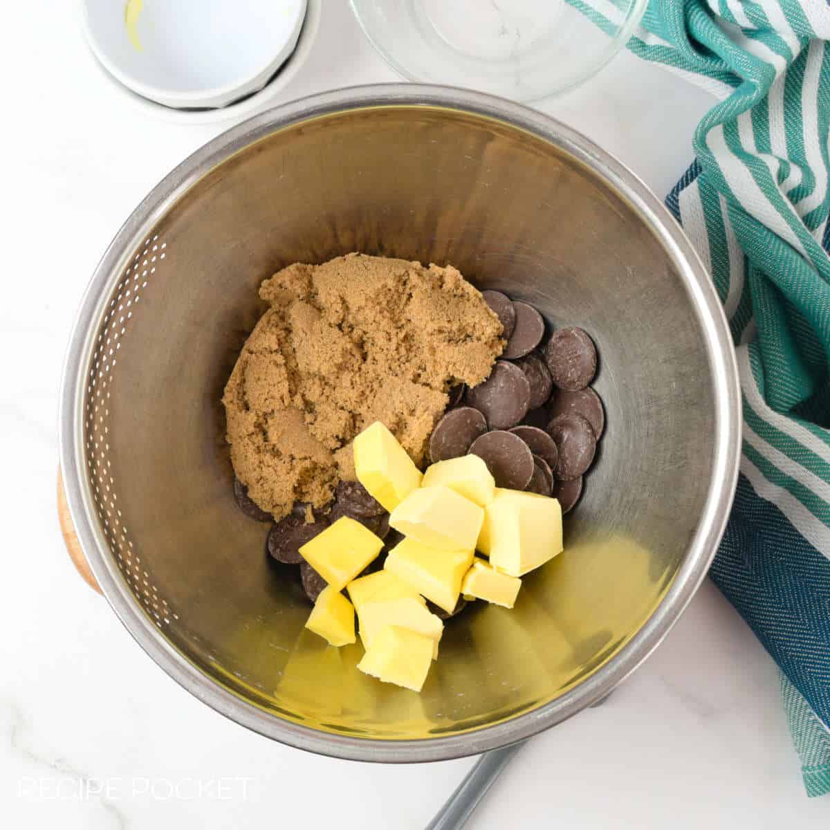 Brown sugar, butter and chocolate in a metal bowl.