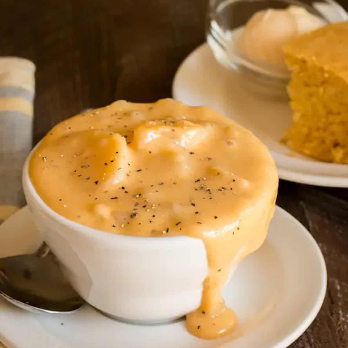 A soup cup over filled with potato soup.