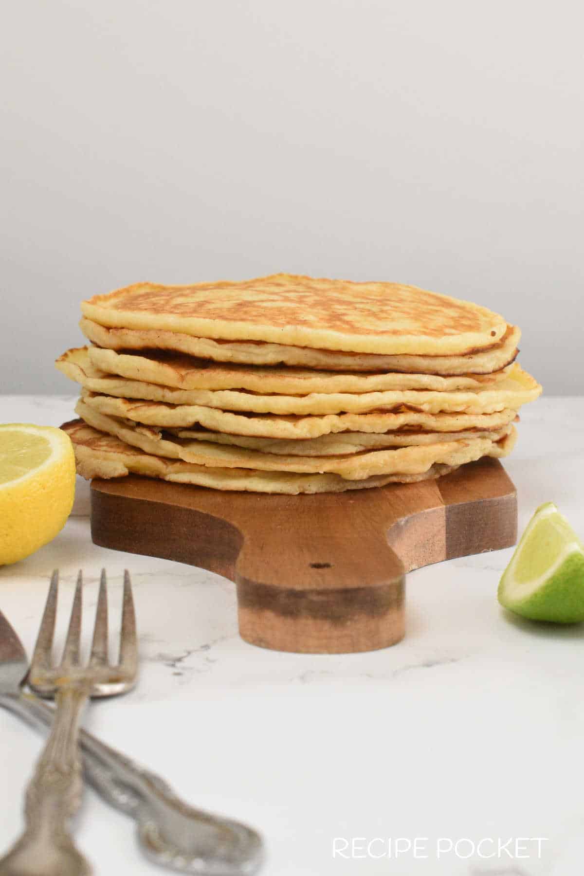 A stack of freshly make ricotta pancakes on a wooden board.