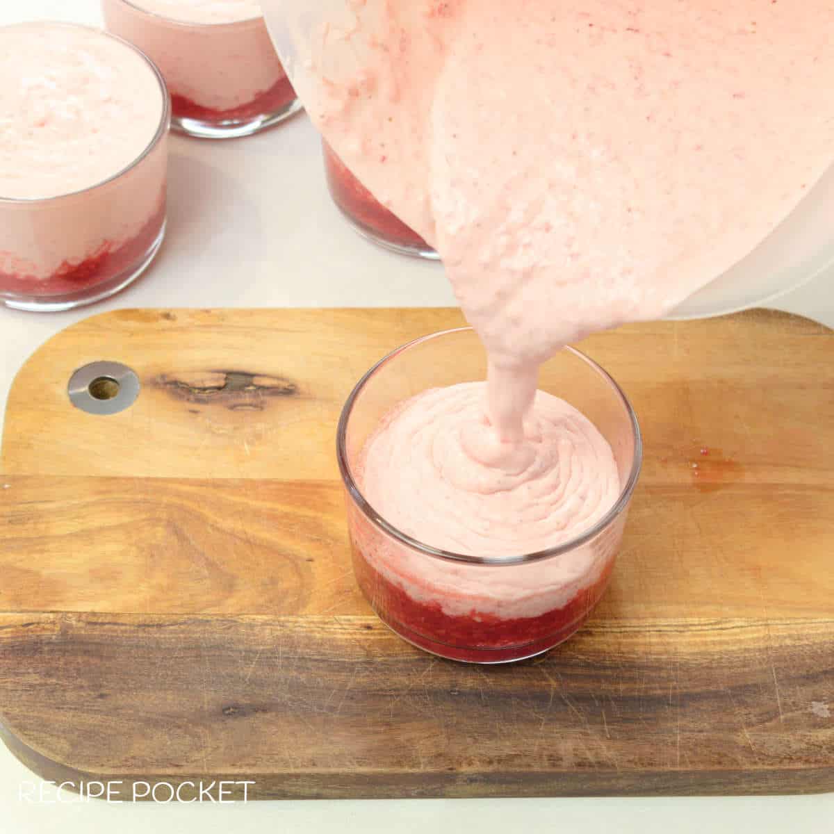 Strawberry cream being poured into a glass.