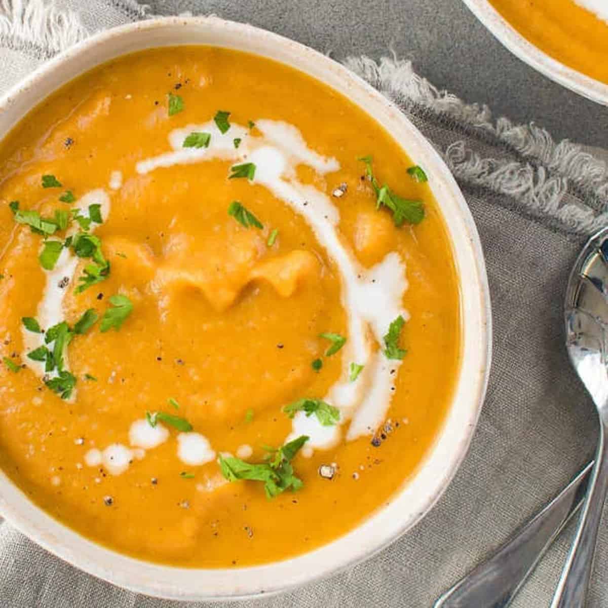 Sweep potato and pumpkin soup garnished with swirls of cream.