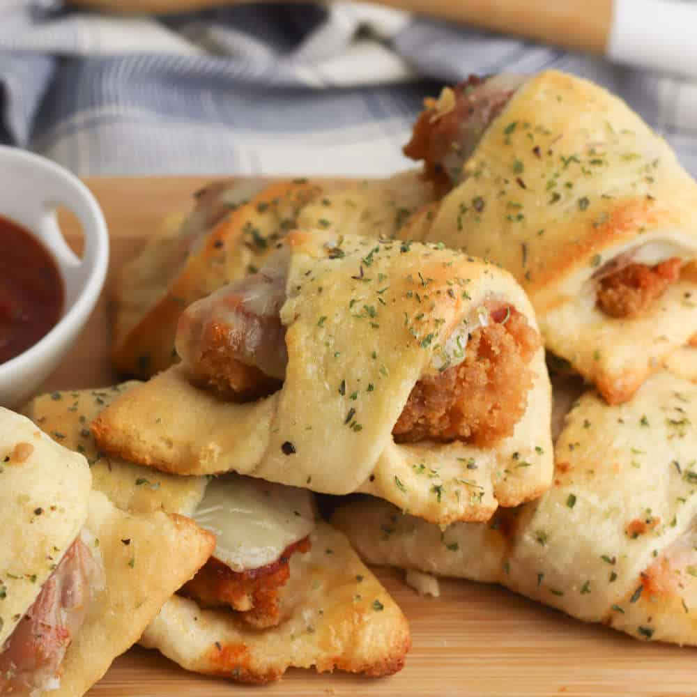 A pile of chicken parmesan rolls. on a wooden board.