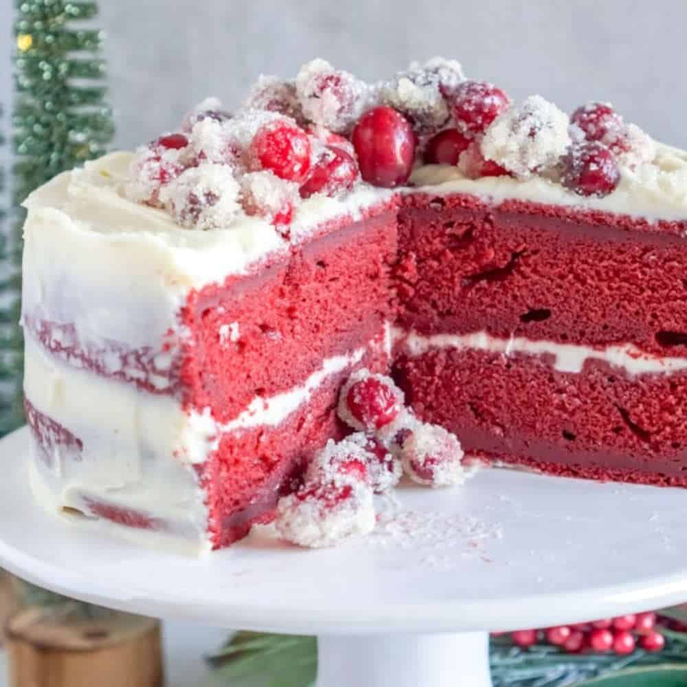 Red velvet cake with white frosting and cranberries on top.