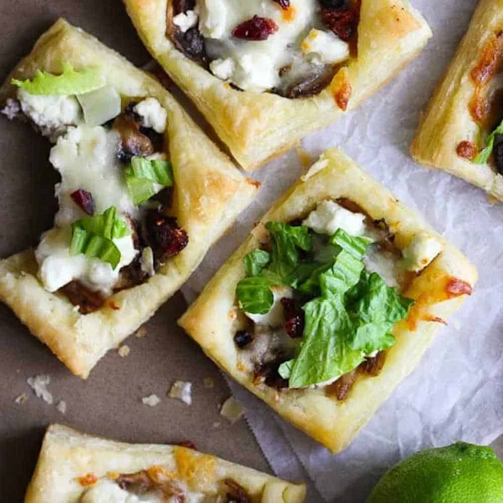 Square puff pasty tarts with goats cheese and shredded lettuce garnish.