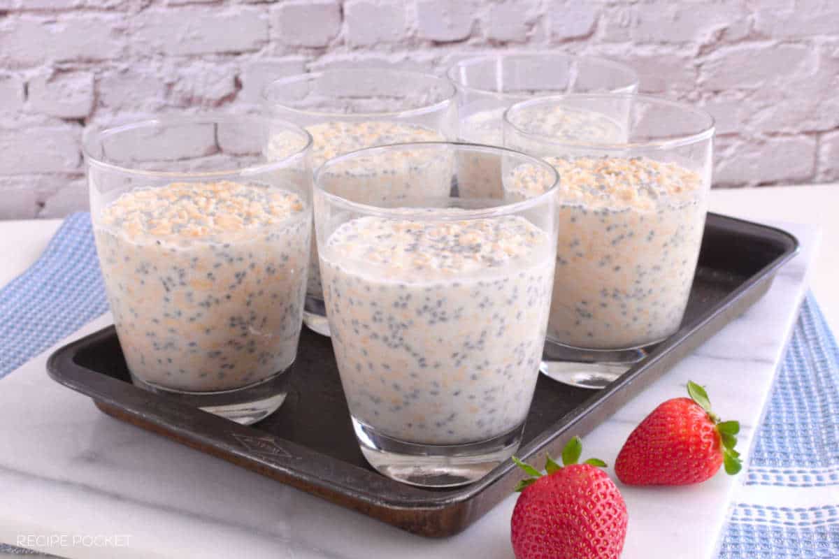 Five servings of easy overnight oats in individual glasses on a black tray.