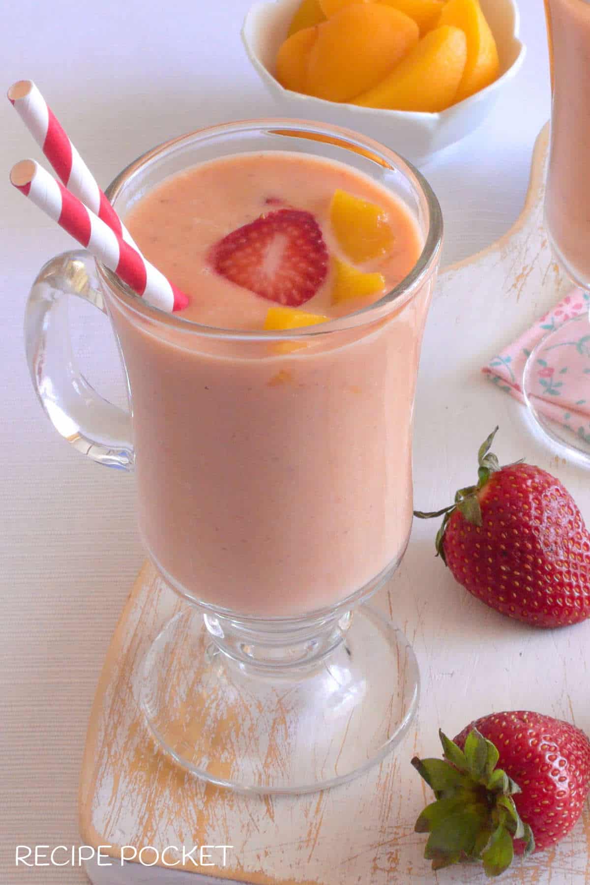A pink fruit smoothie on a white board.