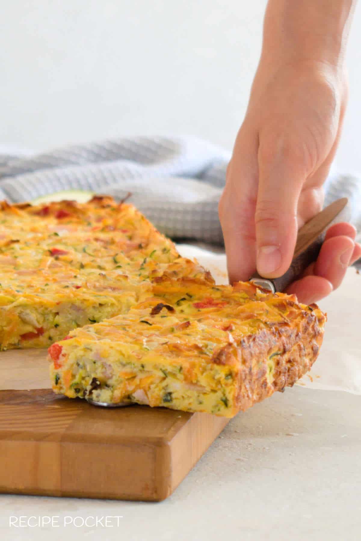 A close up of zucchini and carrot slice on a cake server being held by a hand.