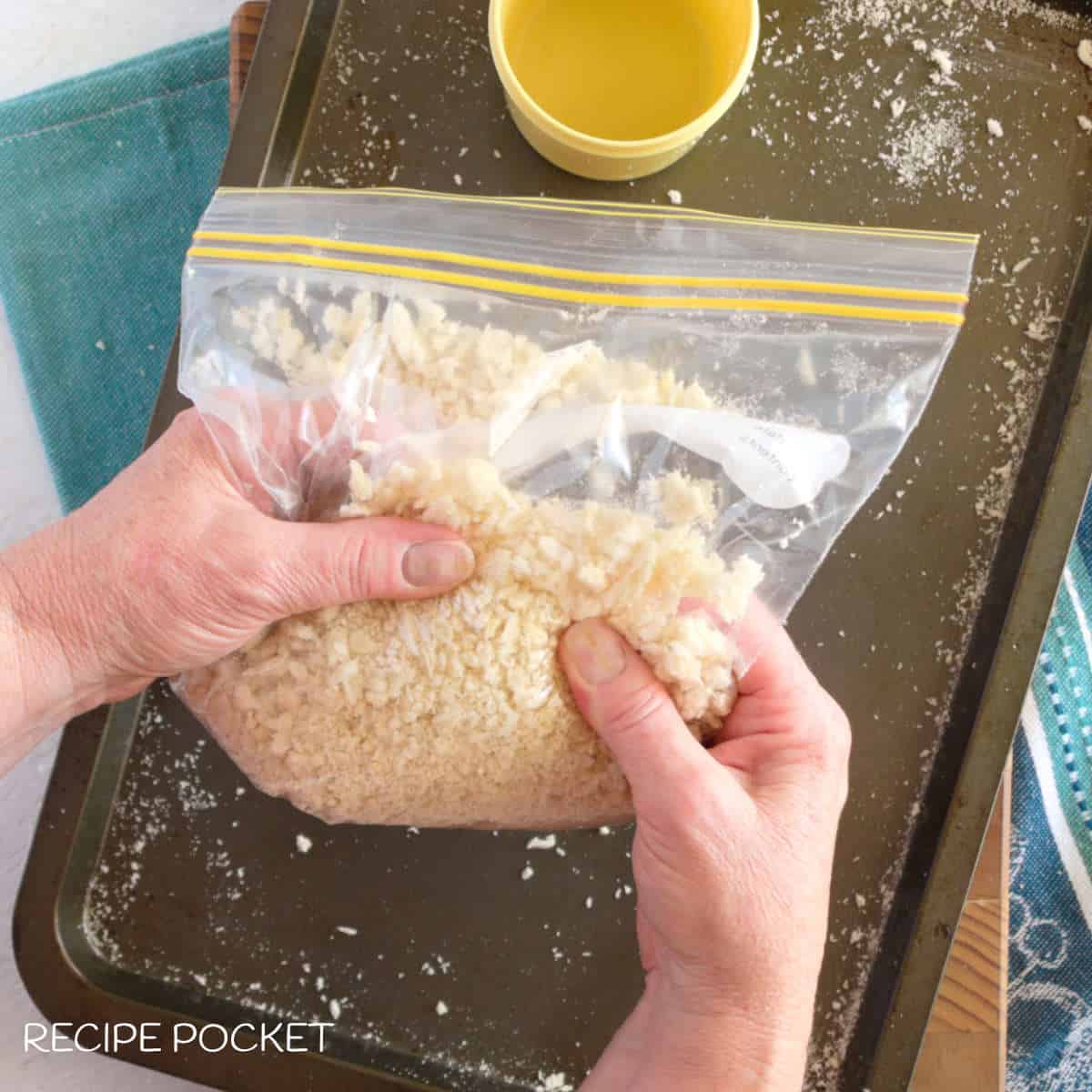 Bread crumbs and a plastic bag being crushed by hand.