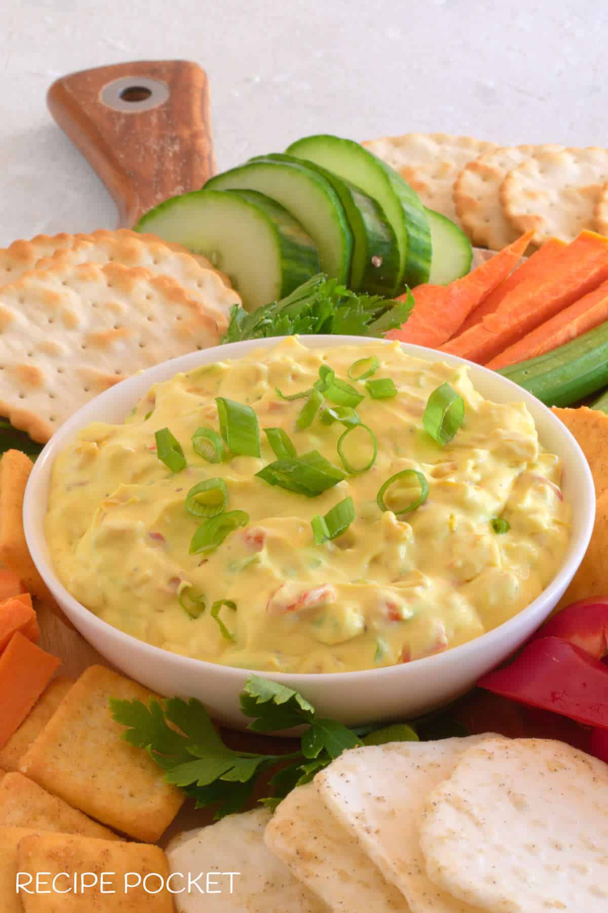 A close up of cream cheese corn dip surrounded by veggies and crackers.