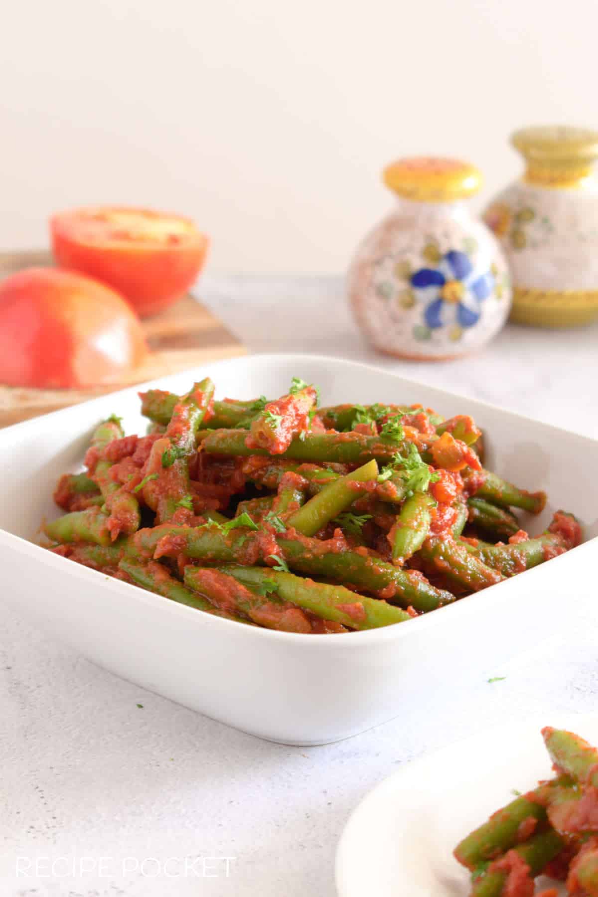 A white bowl filled with Italian green beans in tomato sauce.