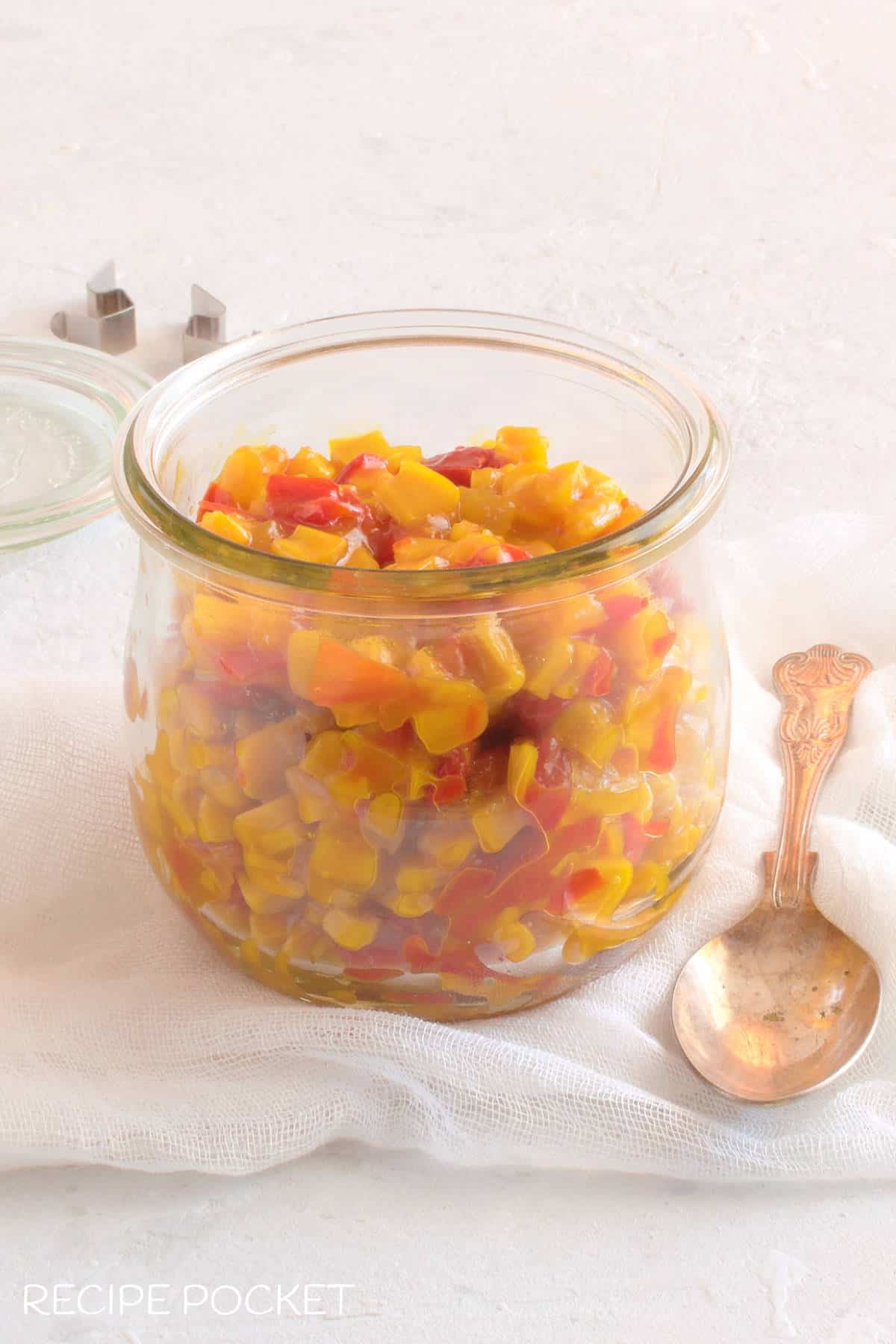 Corn relish in a glass jar with a spoon.