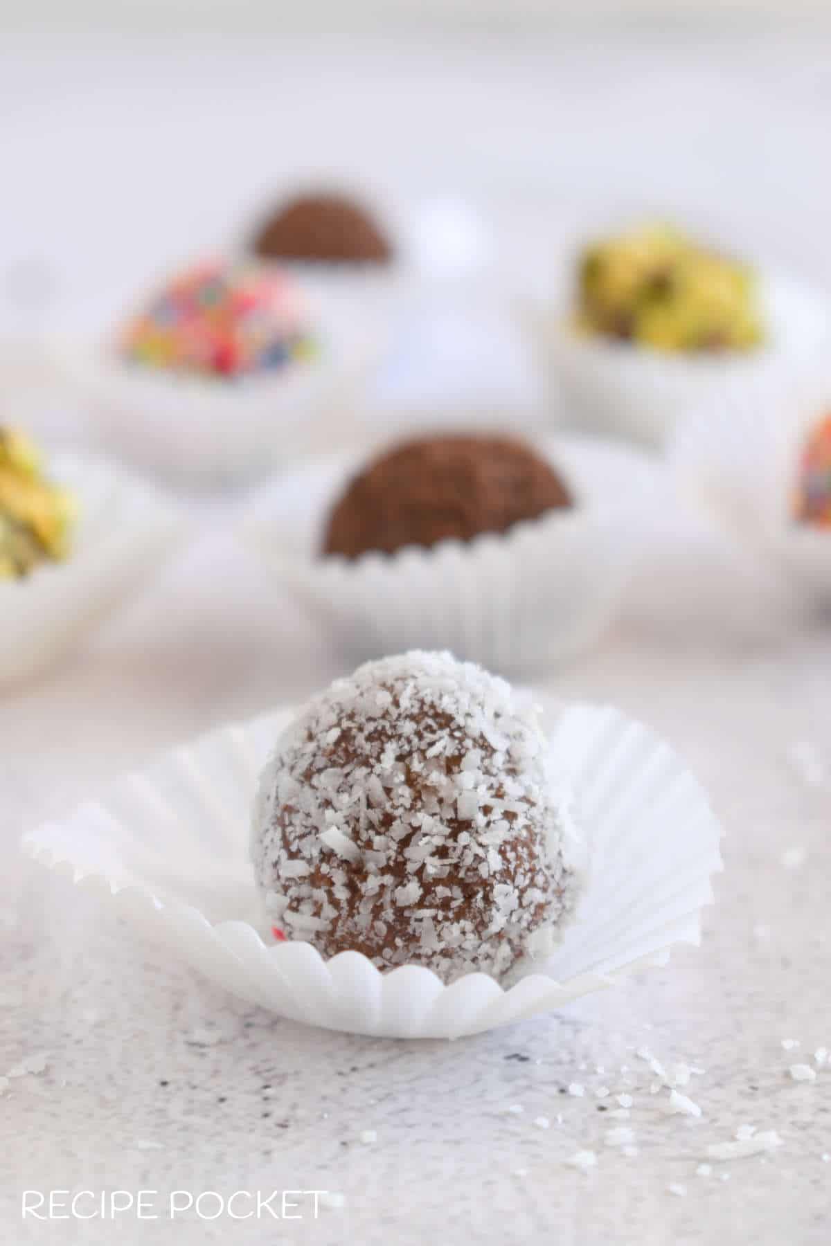 A close up of a truffle made with cake crumbs coated in coconut.