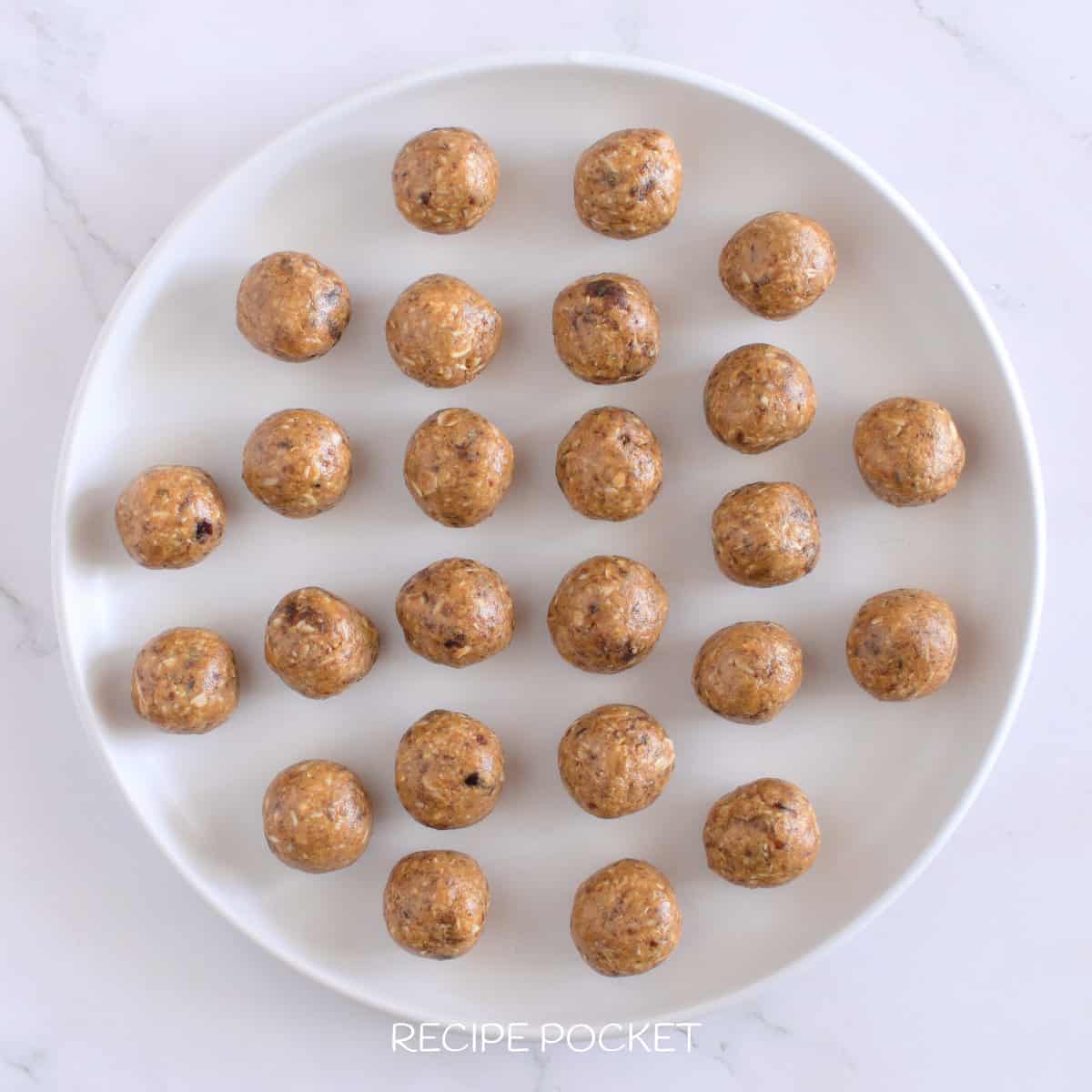 Twenty five peanut butter balls on a white plate.