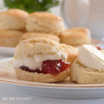 Eggless scones on a plate with jam and cream.