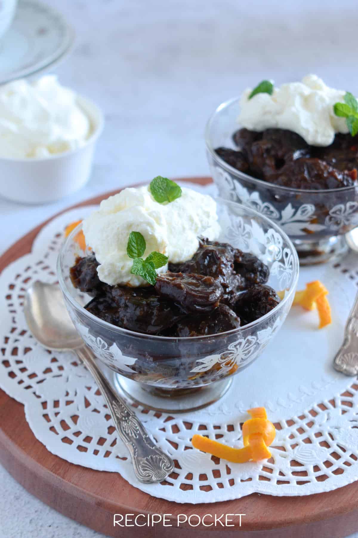 Two bowls of stewed prunes with cream.