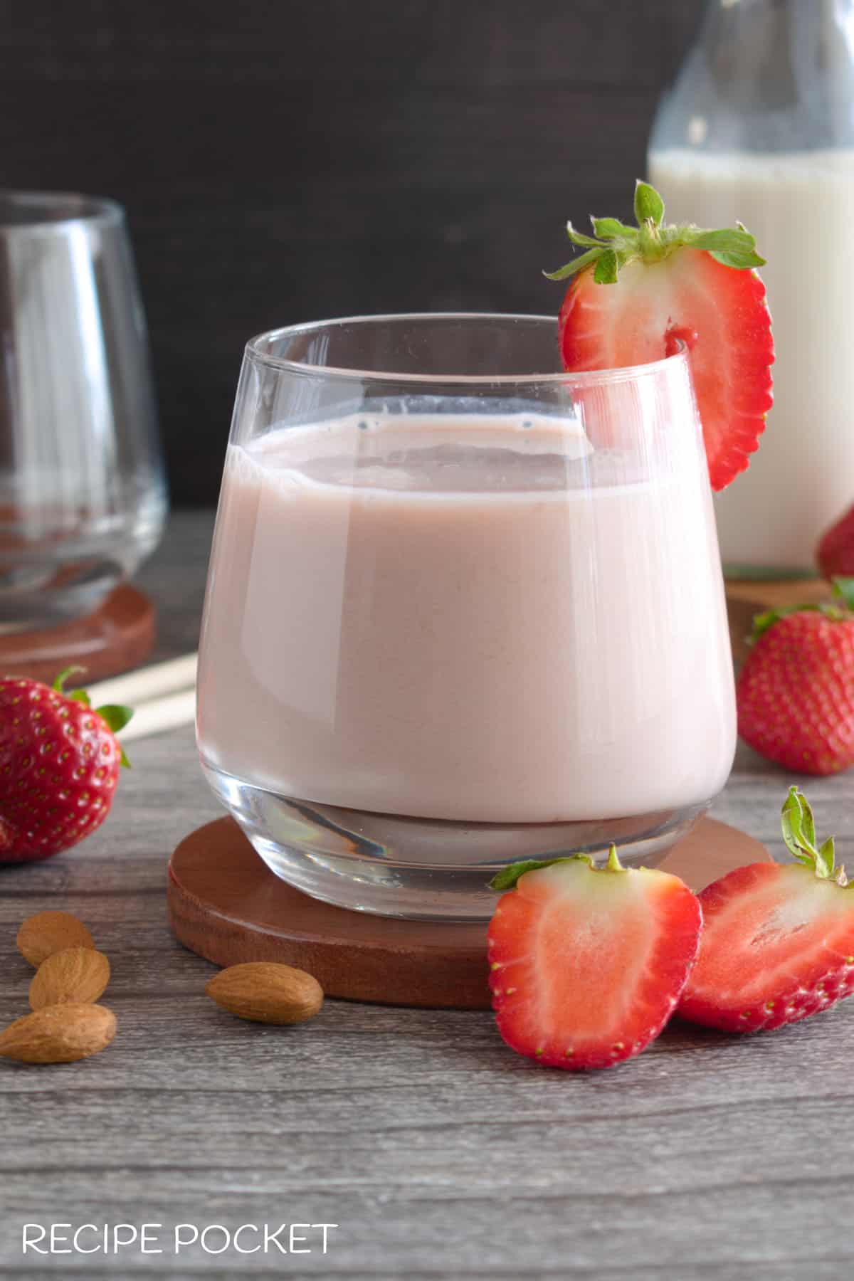 A glass of pink milk garnished with a strawberry.